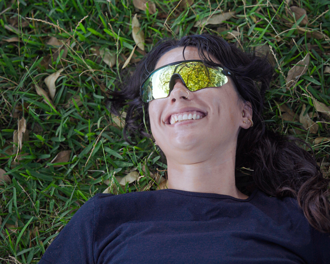 Person wearing reflective sunglasses lying on grass